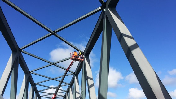 Kontrolleure untersuchen eine Brücke mit Hilfe eines Krans auf Fehler und Mängel. © NDR Foto: Lena Haamann