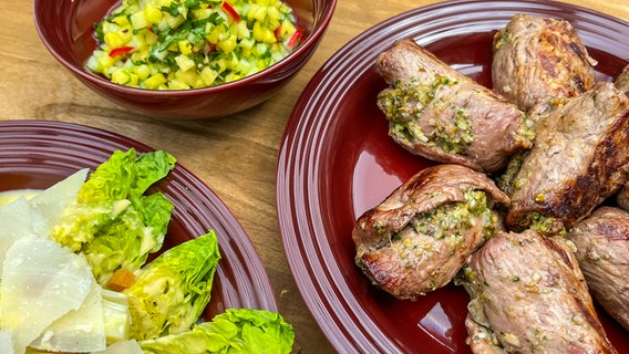 Kalbsröllchen mit Sardellenpaste und Caesar Salad auf einem Teller angerichtet. © NDR 