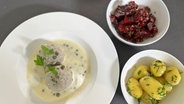 Ein weißer Teller mit Königsberger Klopsen, daneben weiße Schalen mit Rote-Bete-Salat und Salzkartoffeln © NDR 