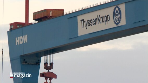Der große Portalkran mit den ThyssenKrupp- und HDW-Logos steht vor leicht bewölktem Himmel in Kiel. © NDR 