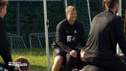 Neuzugang bei THW Kiel Emil Madsen sitzt auf dem Rücken eines anderen Spielers bei einem Training draußen. © NDR 