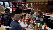 Menschen sitzen an einem Tisch beim Weihnachtsessen für Obdachlose in der Stadtmission Kiel. © NDR 