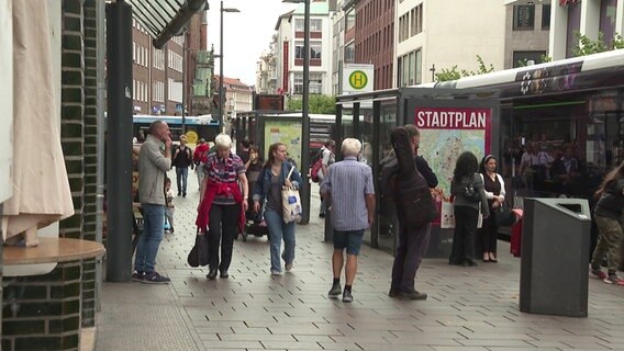 Menschen laufen in der Lübecker Innenstadt an einer Bushaltestelle vorbei © NDR Foto: NDR