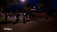 Mehrere Personen warten am frühen Morgen auf einen Bus. © NDR Foto: NDR Screenshots