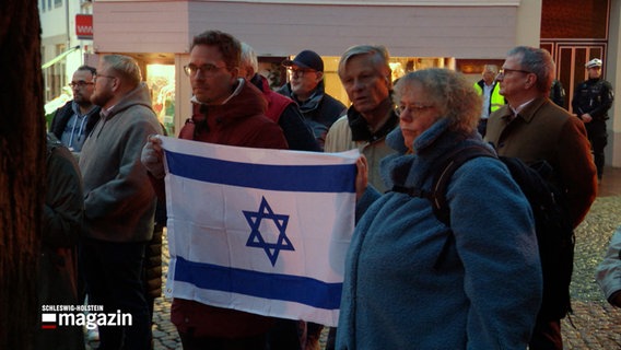 Auf einer Demonstration halten Beteiligte die Flagge Israels in ihren Händen. © NDR Foto: NDR Screenshots