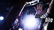 Hände auf einer Party, die in die Luft ragen. Dazu der Text "döp dödö döp" © PA 