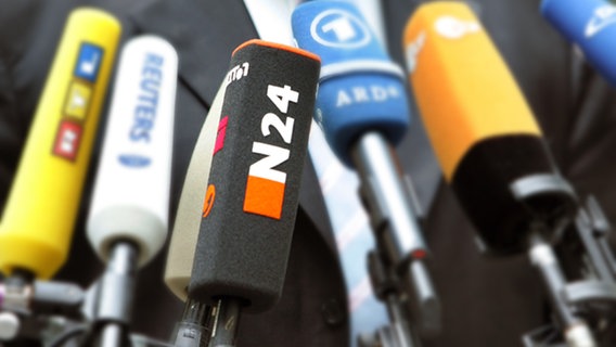 Mikrofone mit verschiedenen Logos sind auf einen Mann mit Krawatte gerichtet. N24 ist scharf zu erkennen, die anderen liegen unscharf im Hintergrund. © picture-alliance/ dpa Foto: Soeren Stache