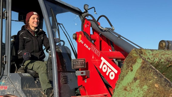 Landwirtin Jessica Lange sitzt hinter dem Steuer eines Baggers und grinst breit. © NDR 