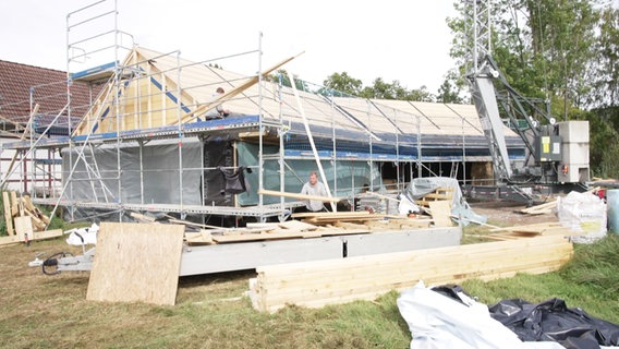 Männer arbeiten am Rohbau eines Hauses aus Strohballen. © NDR 