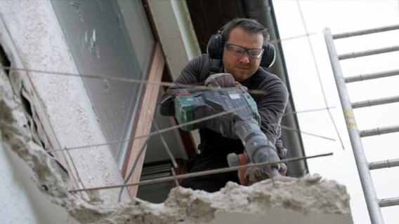 Ein Mann trägt mit schwerem Gerät einen Balkon aus Beton ab. © NDR/Populärfilm/Roland Possehl 