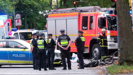 Tödlicher Unfall auf der Langenhorner Chaussee in Hamburg: Fahrzeuge von Polizei und Feuerwehr neben einem Motorrad, dass mit einem Lkw kollidiert war. © TV News Kontor Foto: Screenshot