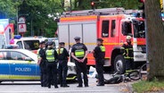 Tödlicher Unfall auf der Langenhorner Chaussee in Hamburg: Fahrzeuge von Polizei und Feuerwehr neben einem Motorrad, dass mit einem Lkw kollidiert war. © TV News Kontor Foto: Screenshot