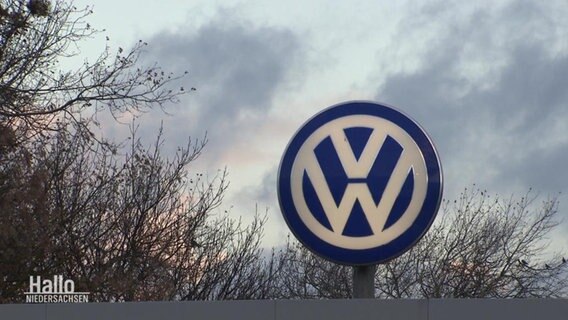 Zu sehen ist das VW-Symbol vor einem wolkenbehangenen Himmel.  