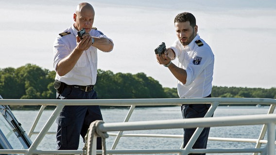 Wolf Malletzke (Christoph Grunert, l.) und Fahri Celik (Hassan Akkouch, r.) stellen auf dem Müggelsee einen Skipper, der eine Leiche an Deck hat. © ARD/Daniela Incoronato 