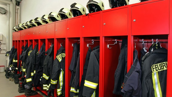 Kleiderspinde in einer Wache der Feuerwehr mit Uniformen und Helmen. © colourbox 