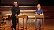 Stefan Gwildis und Annette Frier stehen an zwei Pulten und Lesen © NDR 