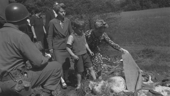 Deutsche Zivilisten, unter ihnen Kinder, müssen sich nach dem Kriegsende die Leichen von Gefangenen aus einem Massengrab anschauen. © National Archives and Records Administration, College Park 