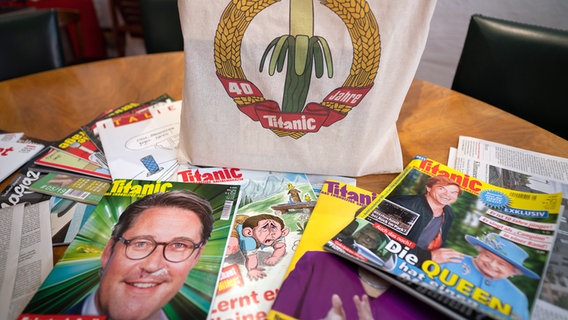 Eine Jubiläums-Stofftasche und einige Ausgaben des Satiremagazins "Titanic" liegen auf dem Konferenztisch in den Redaktionsräumen. © picture alliance/dpa Foto: Frank Rumpenhorst