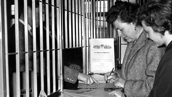 Eine Frau füllt am 24. März 1959 an einem Bankschalter ein Antragsformular für Preussag-Volksaktien aus © picture-alliance / dpa 