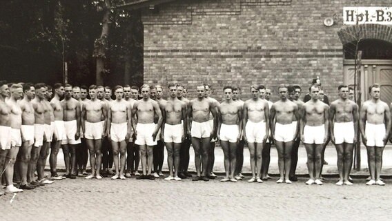 Sportler der Hamburger Turnerschaft stehen aufgereiht mit nacktem Oberkörper.  