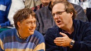 Bill Gates (l.) und Paul Allen, beide Gründer von Microsoft, sitzen während eines Basketball-Spiels der Portland Trail Blazers gegen die Seattle SuperSonics nebeneineander (11.03.2003). © picture alliance/dpa | Foto: Elaine Thompson