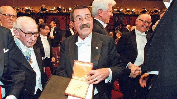 Der deutsche Schriftsteller Günter Grass (M.) zeigt am 10.12.1999 bei einer feierlichen Zeremonie im Konzerthaus in Stockholm die Nobelpreis-Medaille, nachdem er zuvor den Nobelpreis für Literatur erhalten hatte. © picture-alliance / dpa Foto: epa Pressensbild Ekstromer