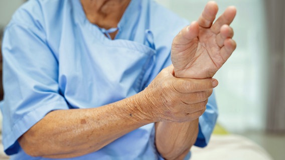 Eine ältere Frau hält sich mit einer Hand das Handgelenk der anderen Hand. © picture alliance / PantherMedia 