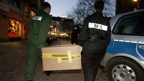 Beamte des BKA tragen am 10.12.2006 im Hamburger Stadtteil Altona eine Kiste mit der Aufschrift "Radioaktiv". © dpa-Bildfunk Foto: Sebastian Widmann