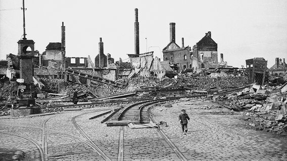 Hildesheim nach den Luftangriffen vom 22. März 1945: Der Sohn des Fotografen, Theo Wetterau Junior, spaziert über den Pelizaeusplatz. Über den Gleisen der Straßenbahn wurden schon die Schienen der Trümmerbahn verlegt. © Theo Wetterau/Verlag Gebrüder Gerstenberg Foto: Theo Wetterau