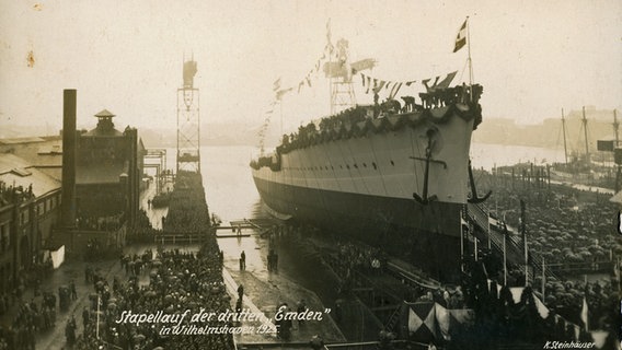 Der Stapellauf der "Emden" am 7. Januar 1925 ist ein Großereignis für Wilhelmshaven. Tausende von Schaulustigen verfolgen das Ereignis vom Rand des Hafenbeckens und den umliegenden Dächern. © Deutsches Marinemuseum Wilhelmshaven 