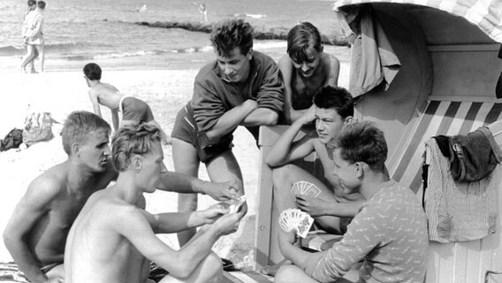 Eine Gruppe junger Männer vertreibt sich während des Urlaubs am Strand von Zingst an der Ostsee die Zeit mit einer Runde Skat, aufgenommen am 15. August 1960. © picture-alliance / dpa Foto: Zentralbild Martin