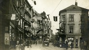 Ein historisches Foto zeigt das Flensburger Zentrum am 14. März 1920 zur Zeit der Grenz-Abstimmung. In der Norderstraße dominierten die deutschen Flaggen - nur ganz klein am oberen Bildrand lugt ein Danebrog ins Bild. © Dansk Centralbibliothek for Sydslesvig/SSF Foto: Unbekannt