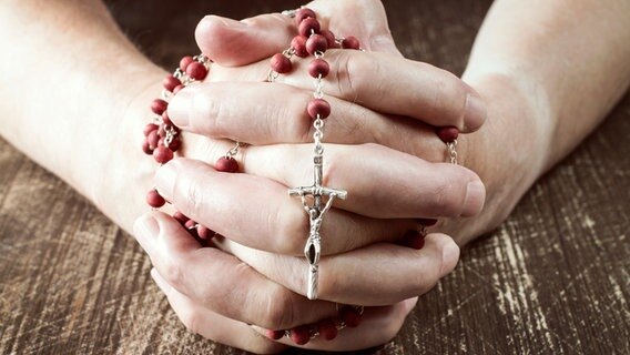 Hände halten einen Rosenkranz in der Hand. © Colourbox Foto: Grazvydas Januska