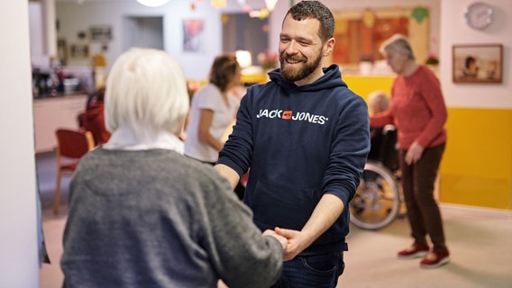 Beim Projekt Musik WG kommen Musiker mit Senioren und Seniorinnen zusammen. Ein Mann hlt die Hand einer Seniorin und lacht. © Bürgerstiftungen Hamburg 