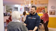 Beim Projekt Musik WG kommen Musiker mit Senioren und Seniorinnen zusammen. Ein Mann hlt die Hand einer Seniorin und lacht. © Bürgerstiftungen Hamburg 