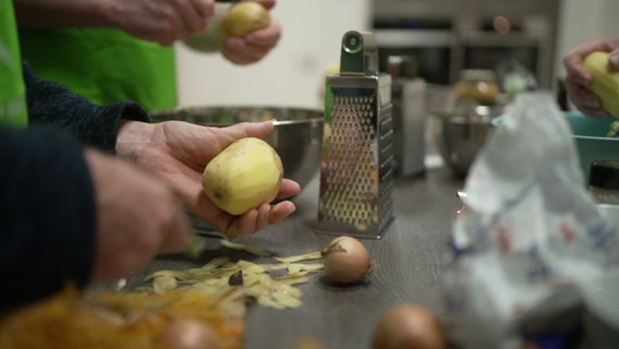 Männerhände schälen bei einem Kochkurs Kartoffeln © NDR 