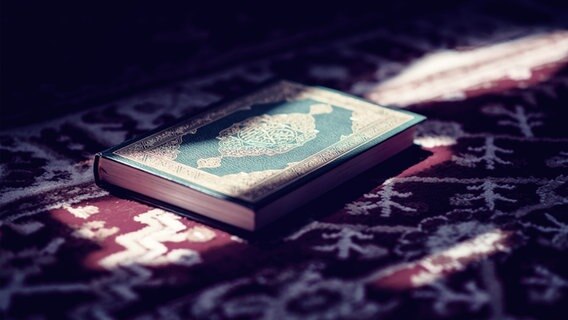 Ein Koran liegt auf einem Teppich, Licht fällt auf das Buch. © Colourbox Foto:  Aida Koric