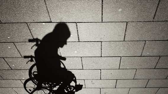 Der Schatten eines Rollstuhlfahrers auf dem Gehweg. © willma  / photocase.de Foto: willma