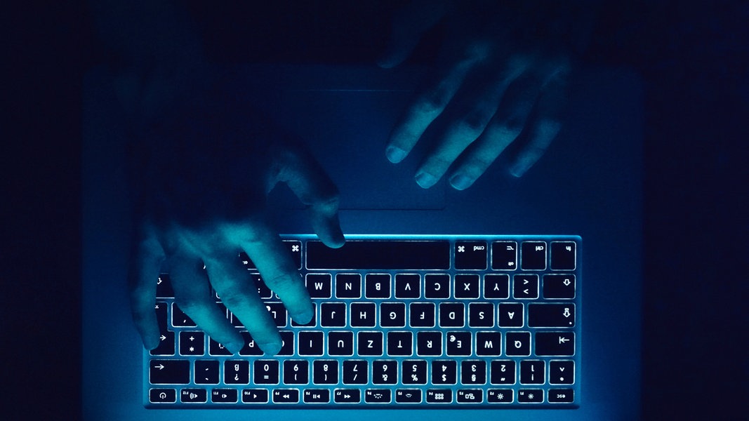 Hände tippen etwas auf einer Computertastatur.