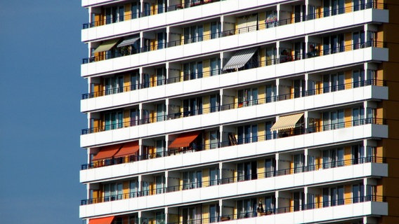 Das Bild zeigt eine Hochhaus-Front mit vielen Fenstern und Balkonen und einigen Markisen. © Photocase Foto: jock+scott