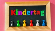 Eine Tafel mit der Aufschrift "Kindertag" in verschiedenen Farben sowie bunten Spielfiguren. © picture alliance / CHROMORANGE Foto: Michael Bihlmayer