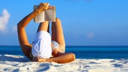 Frau liest am Strand ein Buch © Fotolia Foto: Malbert