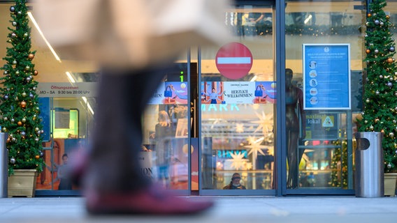 Die Füße einer Passantin unscharf im Vordergrund, dahinter ein geschlossenen Geschäft. © picture alliance/dpa/dpa-Zentralbild Foto: Sebastian Kahnert