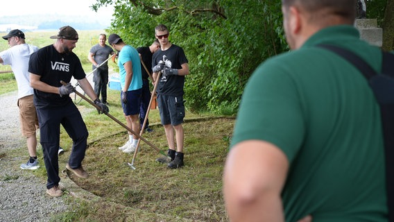 Die Vereinsmitglieder des Herrenclub Barienrode arbeiten mit Hacken am Beet des Wanderkreuzes. © NDR Foto: J. Bockemüller / M. Seemann