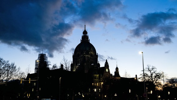Dunkle Wolken ziehen in der Abenddämmerung über das Neue Rathaus hinweg. © picture alliance / dpa Foto: Julian Stratenschulte