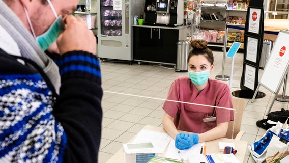 Eine Krankenschwester beobachtet, wie sich ein Patient einen Mundschutz anlegt. © dpa-Bildfunk Foto: Frank Molter