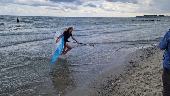 Eine Frau auf einem Stand-up-paddle-Board paddelt zu einer Person im Wasser © NDR Foto: Dominik Dührsen