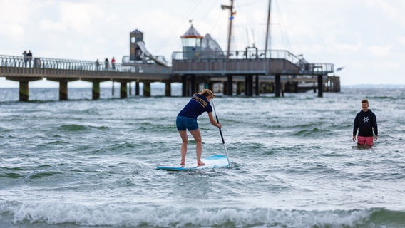 Eine Frau auf einem Stand-up-paddle-Board paddelt zu einer Person im Wasser © NDR Foto: Dominik Dührsen