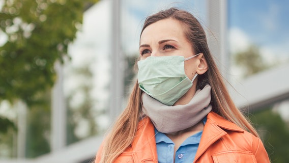 A young woman in front of a building wearing a protective mask.  © Colourbox Photo: Kzenon