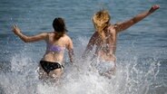 Blick von hinten auf zwei junge Frauen, die im Meer baden. © picture alliance Foto: Carsten Rehder